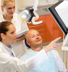 A male patient looking at a screen his dentist is pointing to