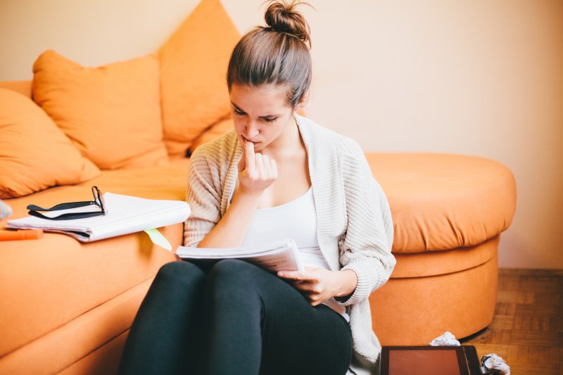 Woman at home reading paper and biting her nails
